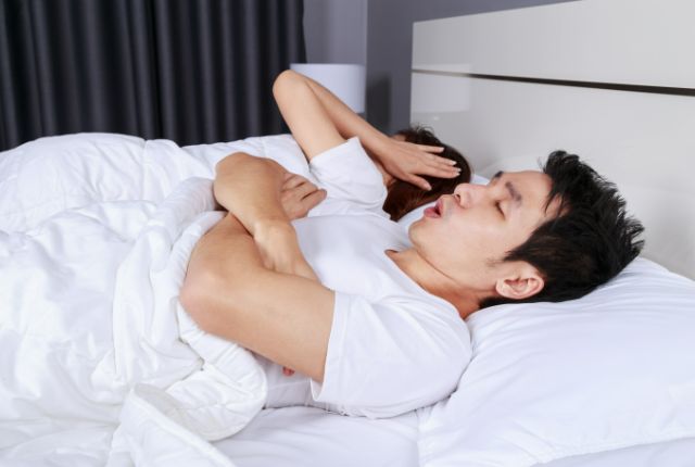 いびきをかく男性と耳をふさぐ女性